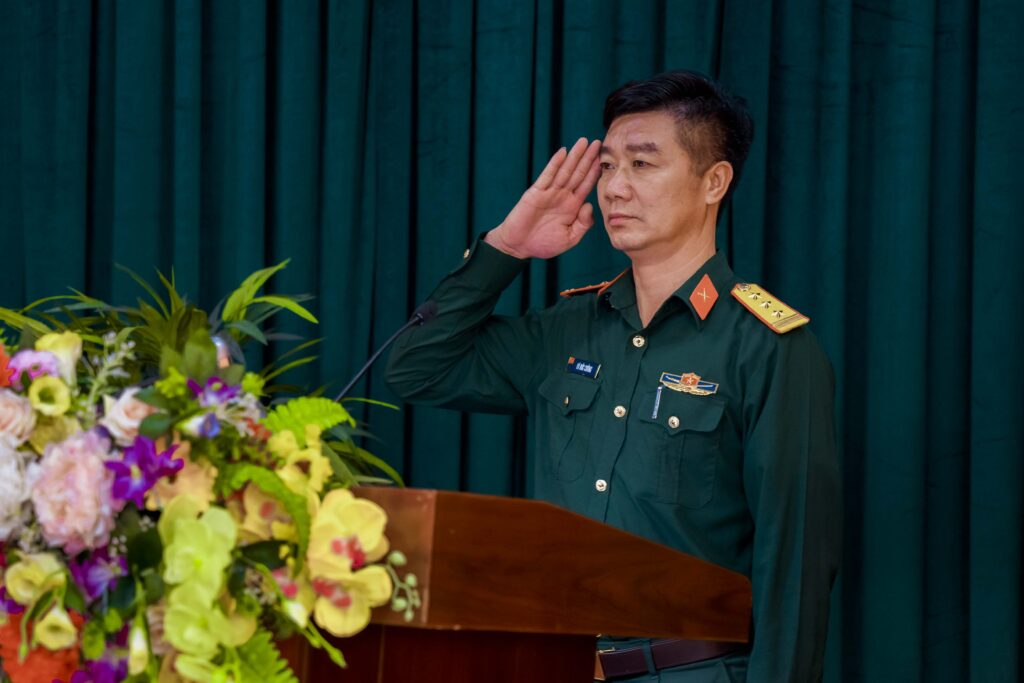 A Vietnamese military officer rendering a salute at a podium.