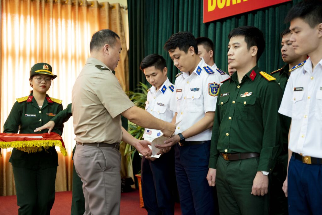A US colonel presents a Vietnamese lieutenant with a graduation certificate.