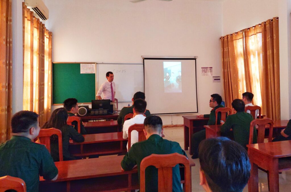 Teacher and students in a classroom watching a video on a projector.